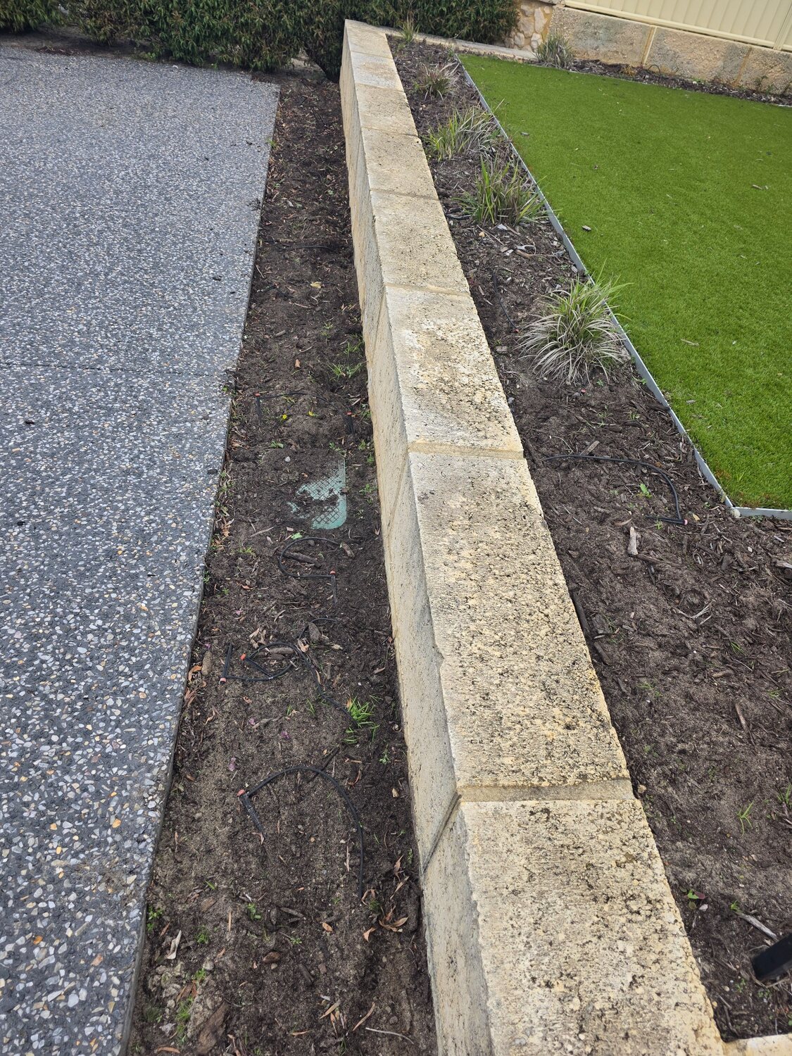 Exposed aggregate driveway and retaining wall before cleaning